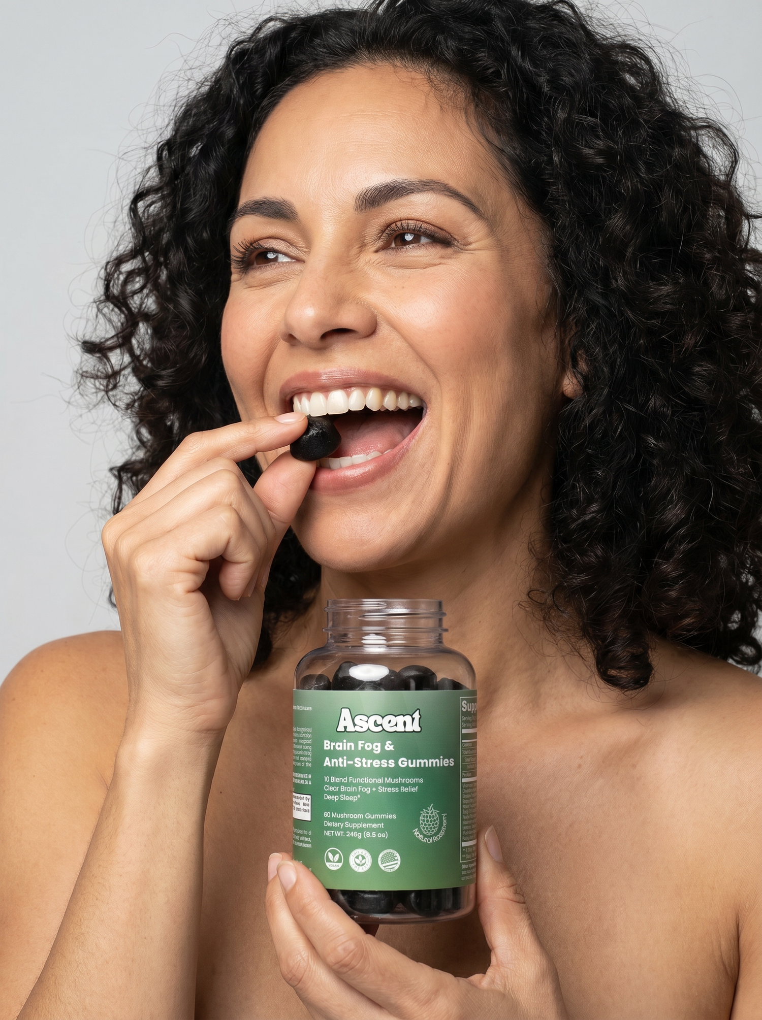 Woman holding a bottle of Ascend vitamins with a gray background